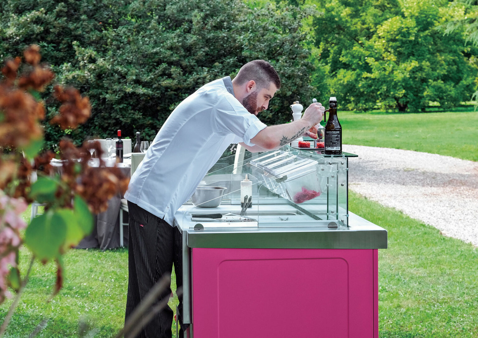 Chef préparant des produits frais sur une station réfrigérée Grab and Go à façade rose